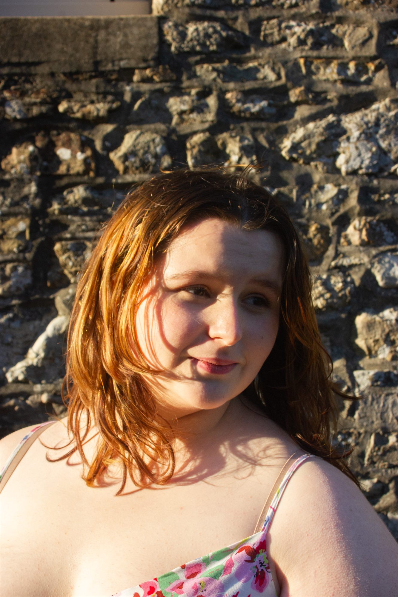 Portrait à la golden hour devant un mur de pierre