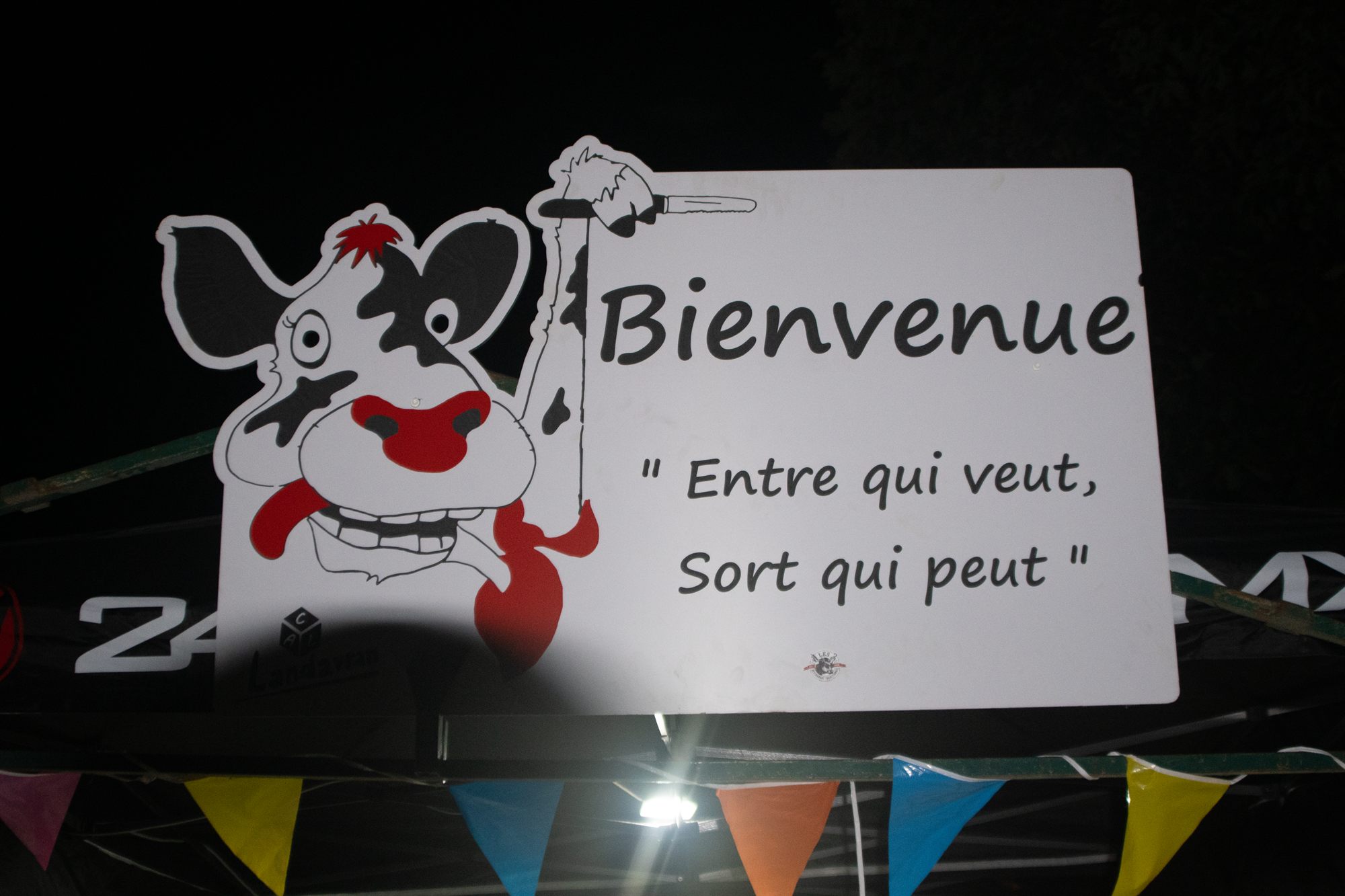 Panneau « Bienvenue — entre qui veut, sort qui peut » avec vache dessinée, fête du veau de Pentecôte